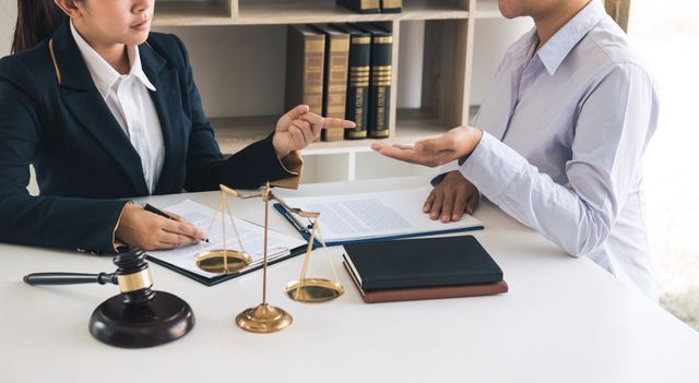 A lawyer is sitting at a desk talking to a client.
