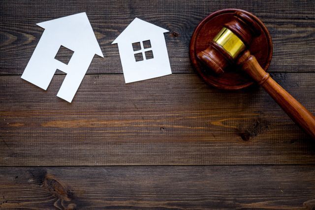 A judge 's gavel is sitting on a wooden table next to paper houses.