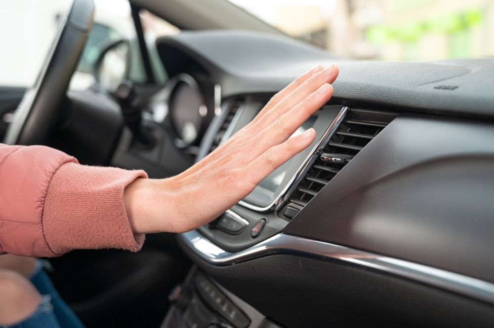 A person is pressing a button on the dashboard of a car.