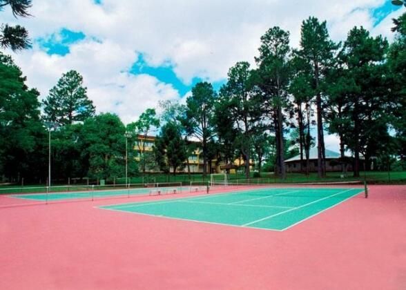 Uma quadra de tênis com árvores ao fundo em um dia nublado