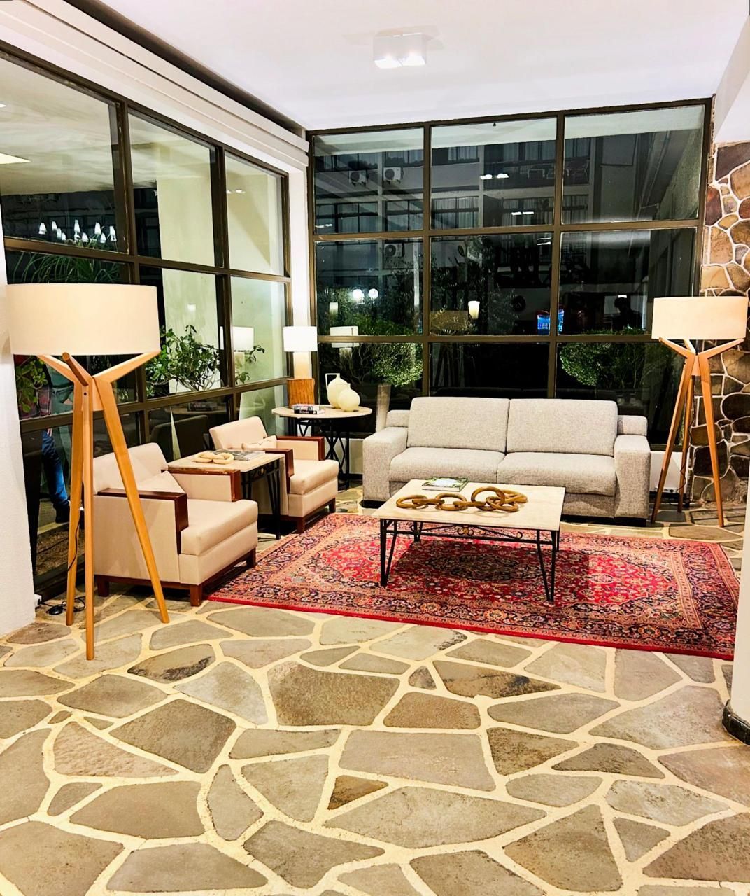 Uma sala de estar com um sofá, cadeiras, luminárias e um tapete