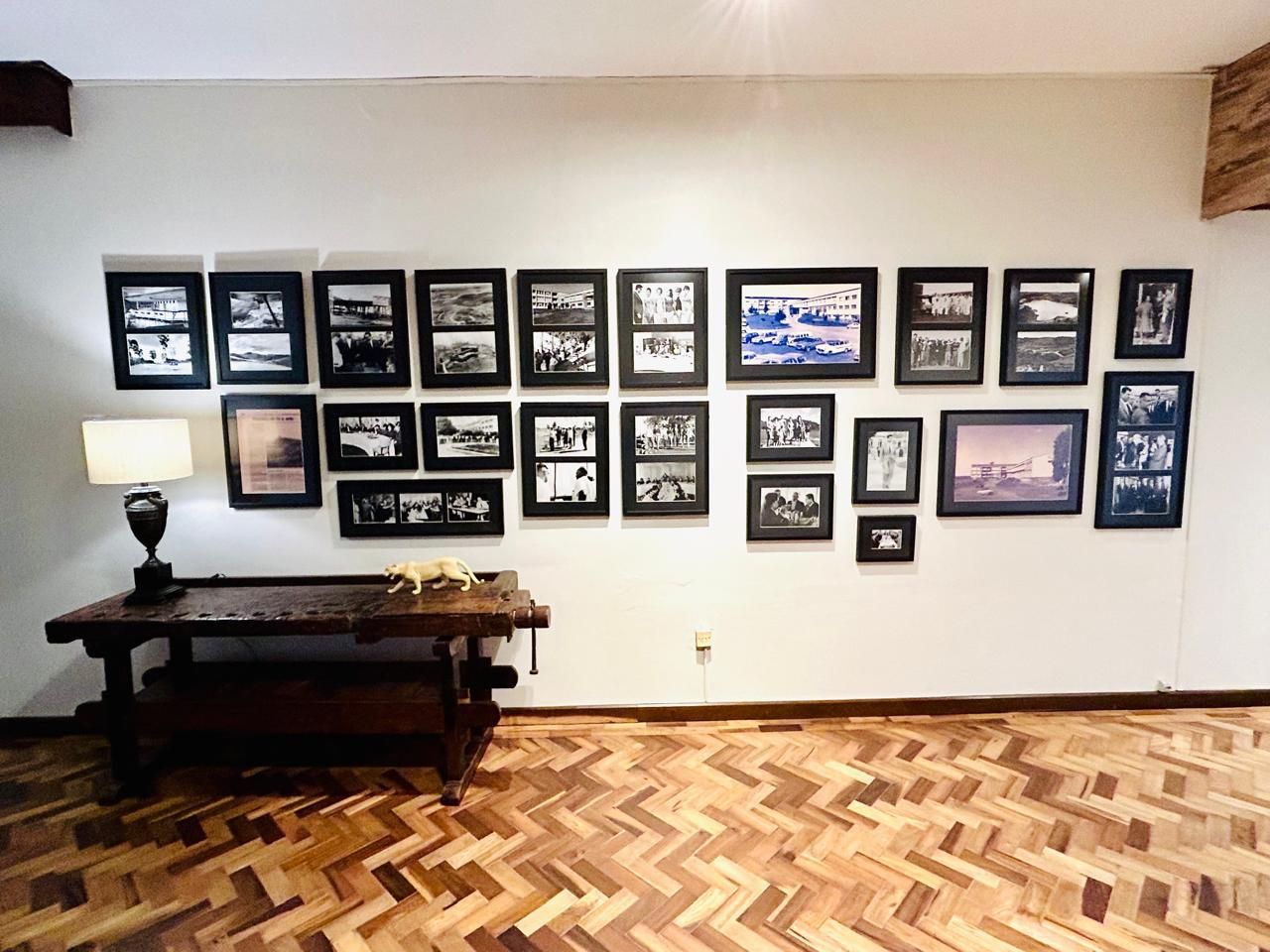 Uma sala com piso de madeira e uma parede cheia de quadros.