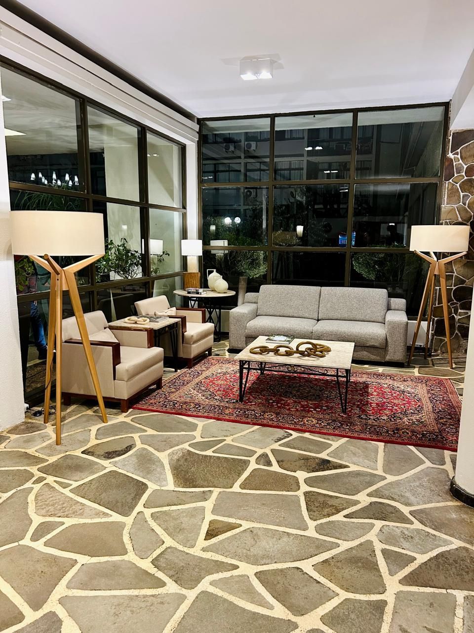 Uma sala de estar com um sofá, cadeiras, luminárias e um tapete.