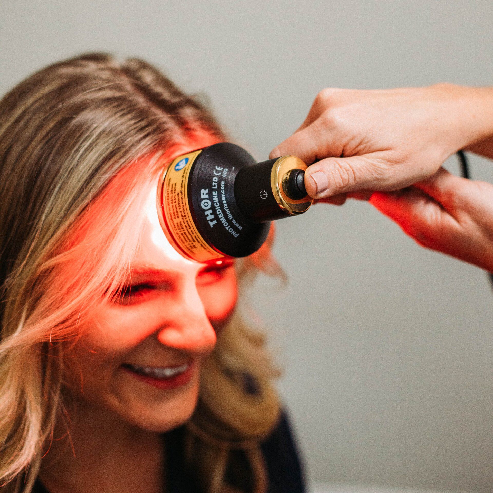 Woman receiving photobiomodulation light therapy treatment on forehead