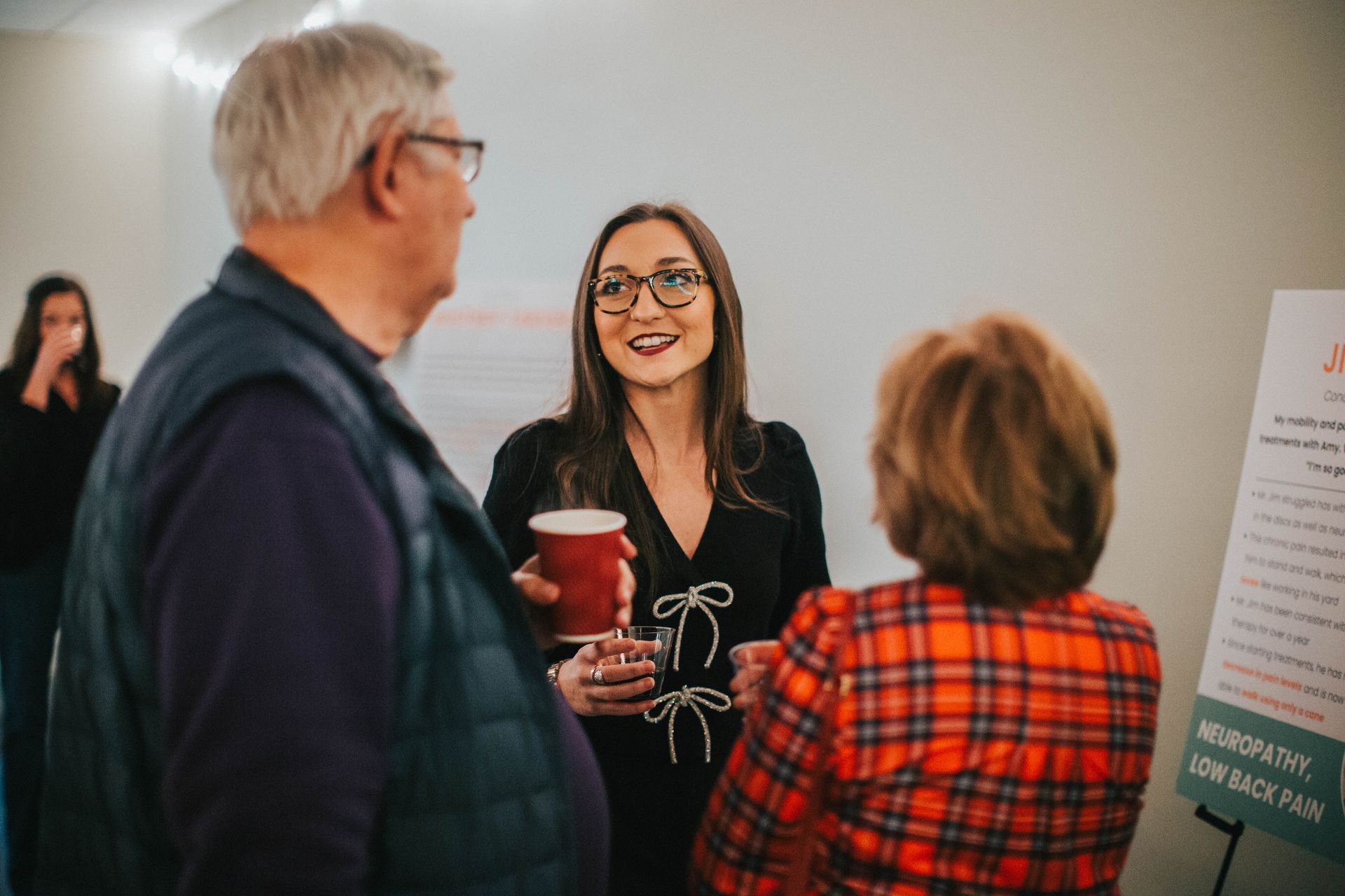 A group of people are standing in a room talking to each other.