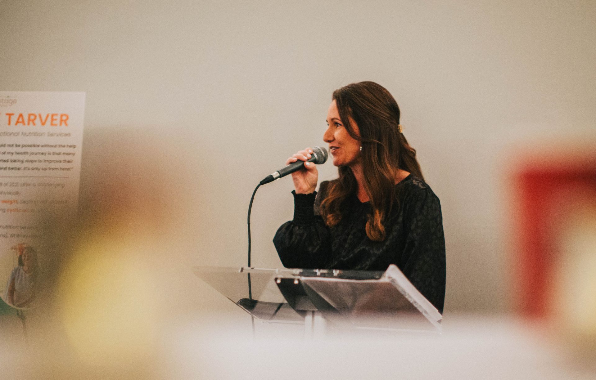 A woman is talking into a microphone while standing at a podium.