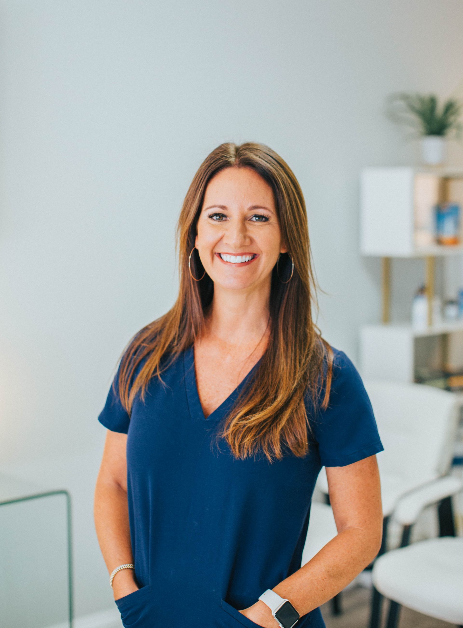 a woman in a blue scrub top smiles for the camera