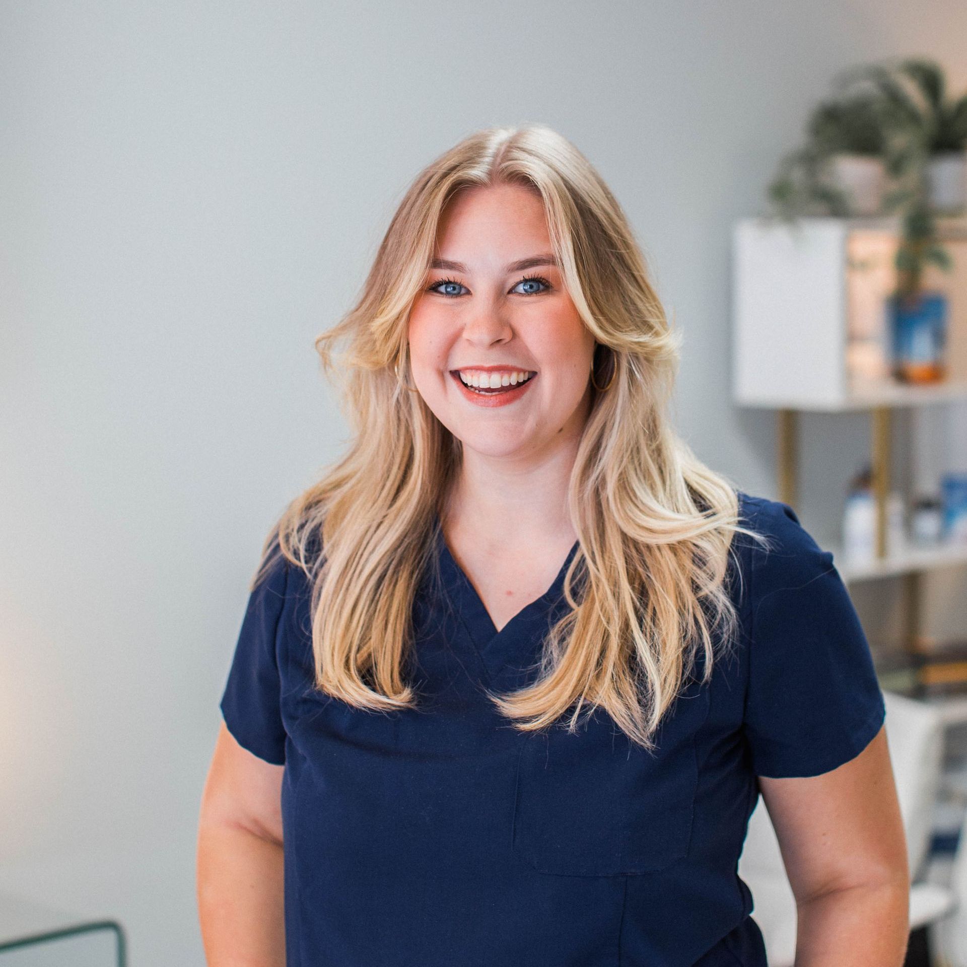 a woman in a blue scrub top is smiling for the camera .