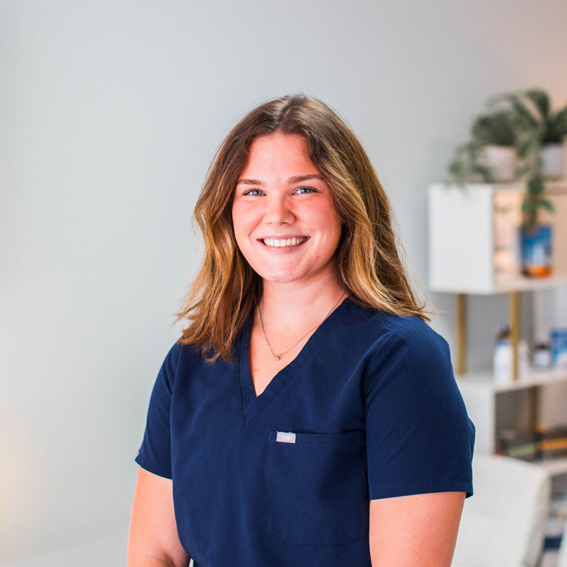 a woman in a blue scrub top is smiling for the camera .