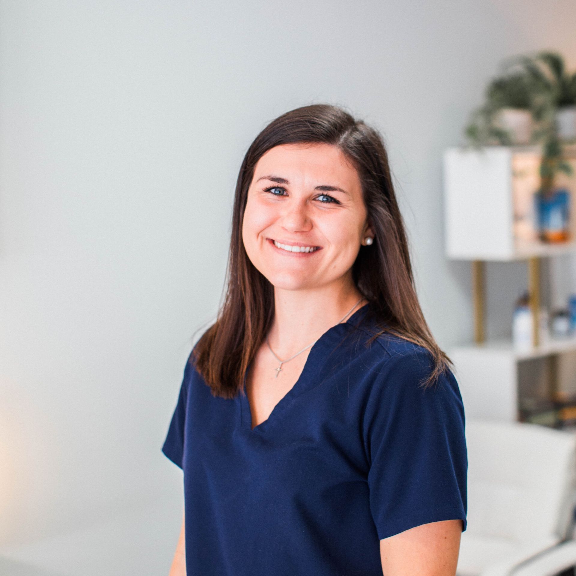 a woman in a blue scrub top is smiling for the camera