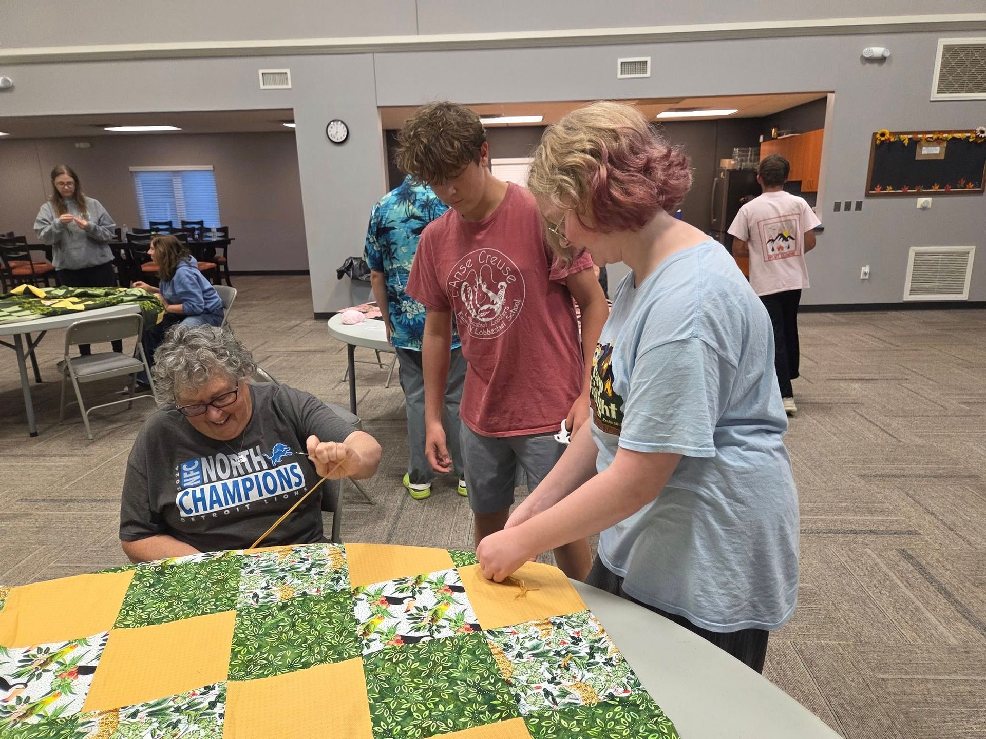 Man sewing intricate embroidery in a colorful shop filled with textiles.