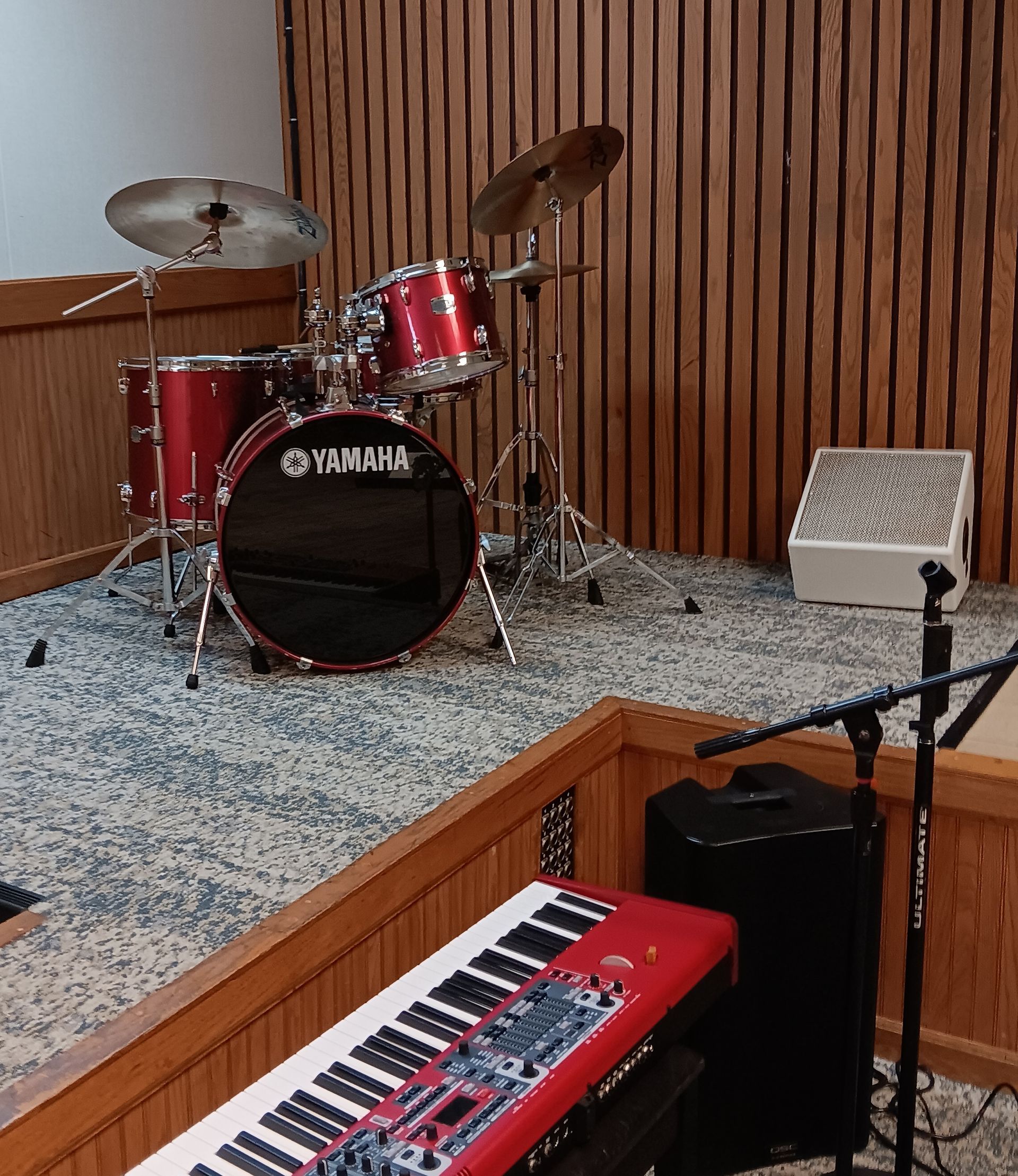 A band and singers perform on a stage with a quilt-covered table in the foreground. They are lit by stage lights.