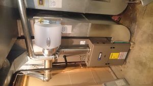 Furnace and humidifier in a basement. Silver ductwork and a humidifier tank are visible.