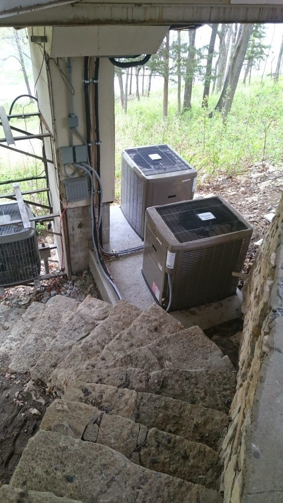Stone stairs leading up to two outdoor air conditioning units.