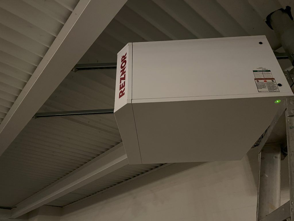 White Reznor heater mounted on a ceiling in a commercial building.