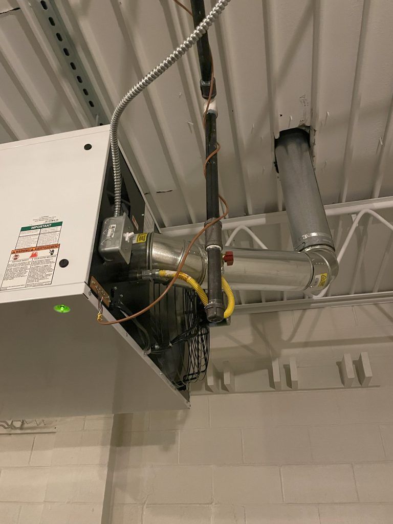 White overhead gas heater with exhaust pipe in a commercial setting.