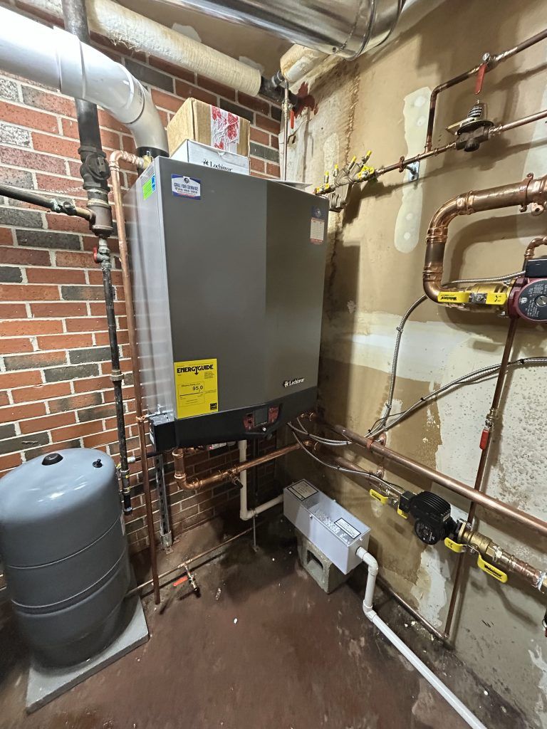 A gas boiler with copper pipes, an expansion tank, and other heating system components in a basement setting.