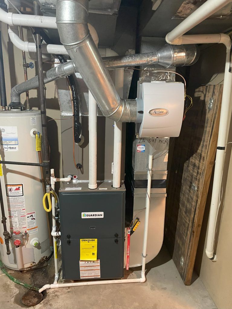 Furnace and humidifier system in a utility room with water heater and ductwork.