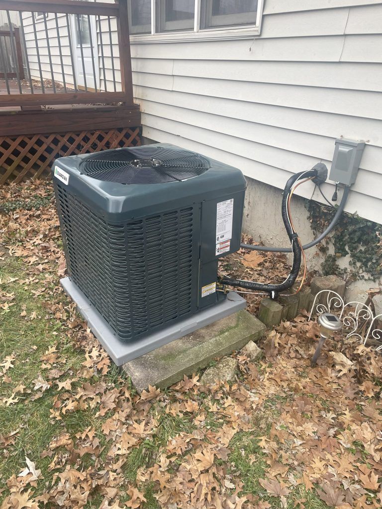 HVAC unit next to a house.  Outdoor unit on a concrete pad, with electrical box.