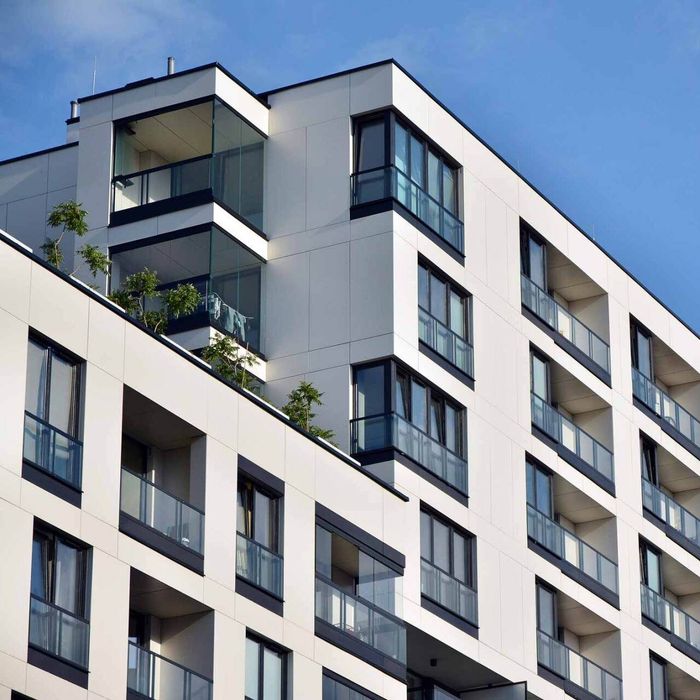 A large apartment building with a lot of windows and balconies against a blue sky.