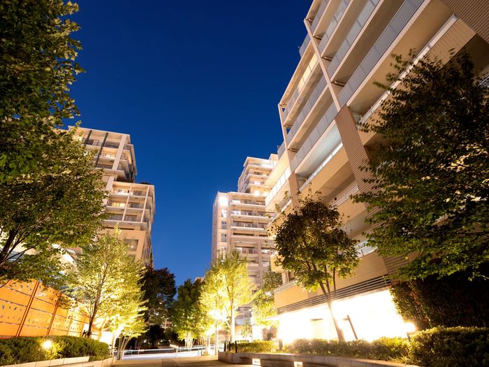 A row of tall buildings are lit up at night.