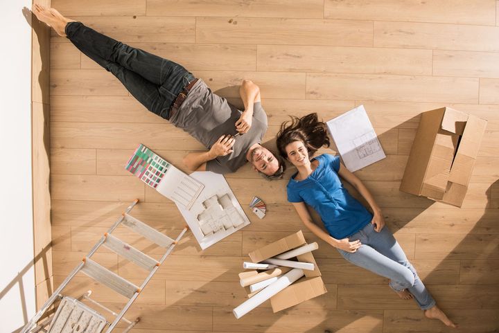 A man and a woman are laying on the floor in their new home.