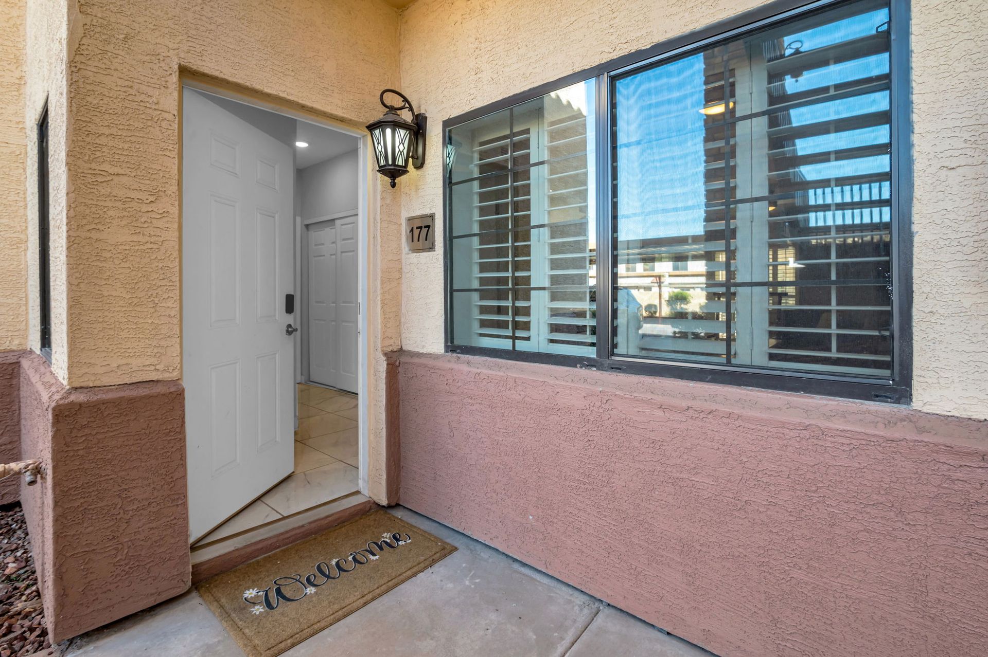 Open doorway with welcome mat, window, and exterior of a home.
