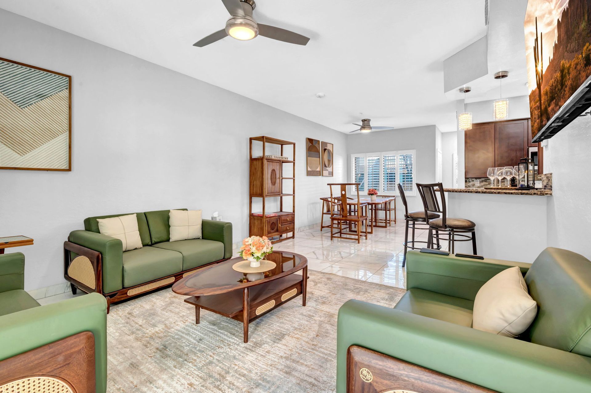 Green living room with matching sofa and chairs, wooden furniture, and light gray walls.