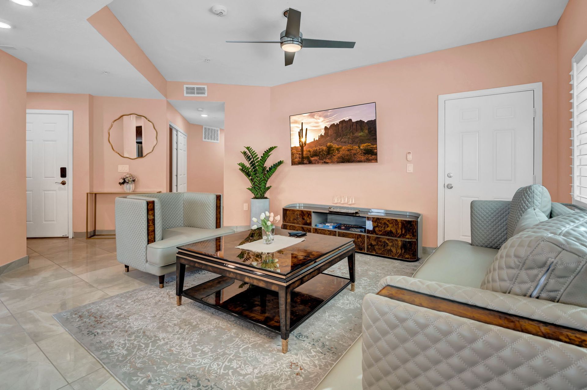 Living room with pink walls, gray furniture, and a TV; centered on a dark coffee table.