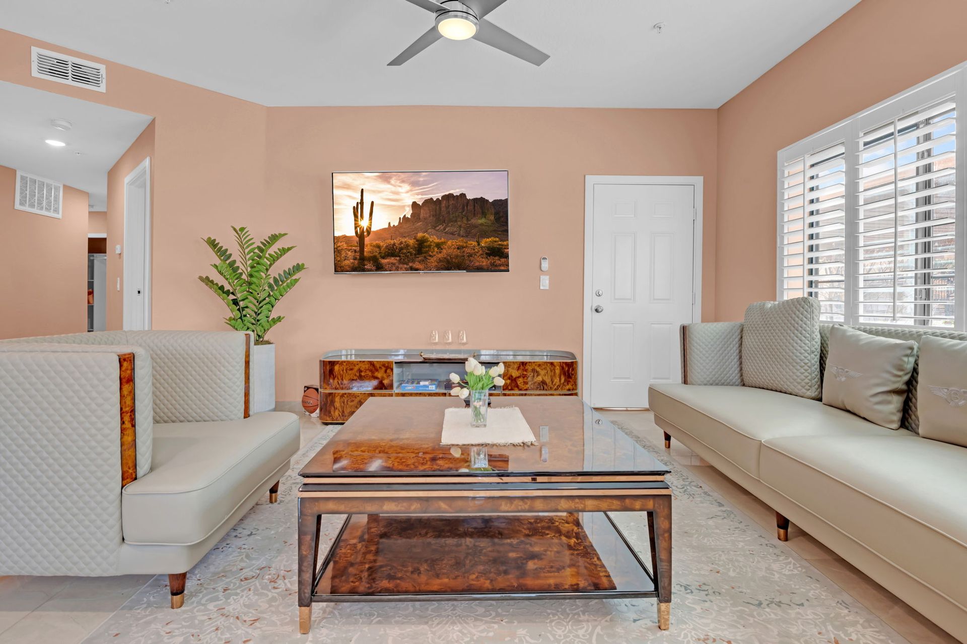 Living room with beige furniture, peach walls, and a mounted TV.
