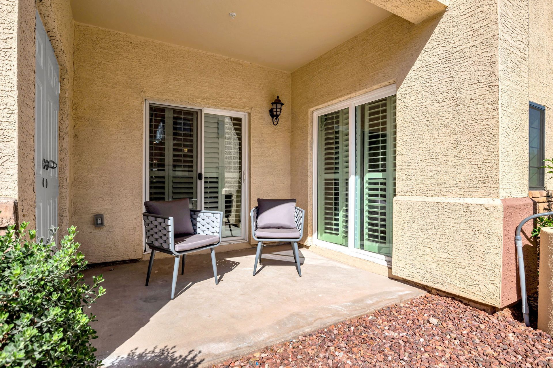Patio with two chairs, sliding glass door, and stucco wall.