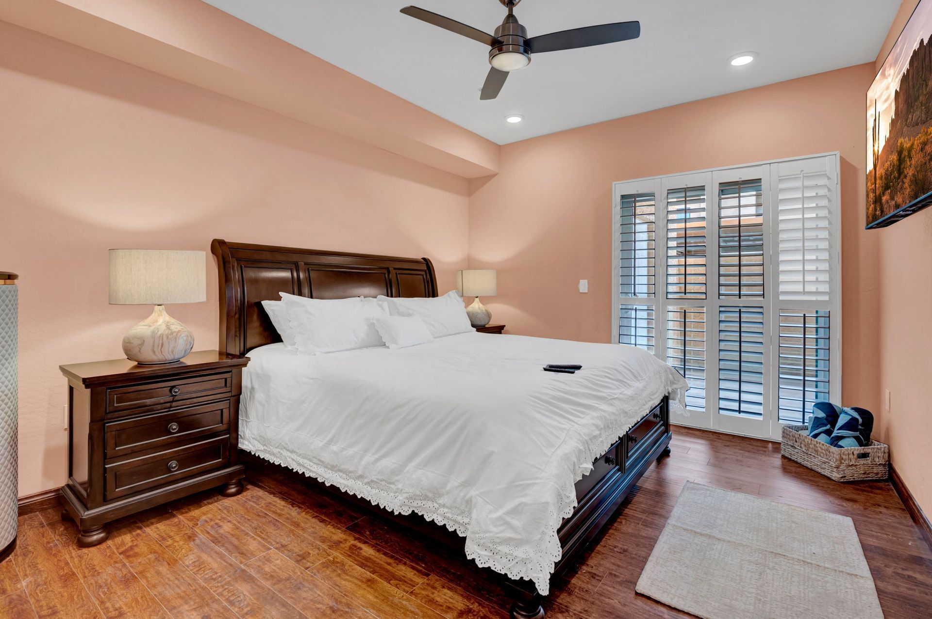 Bedroom with dark wood furniture, peach walls, white bedding, and a shuttered door.