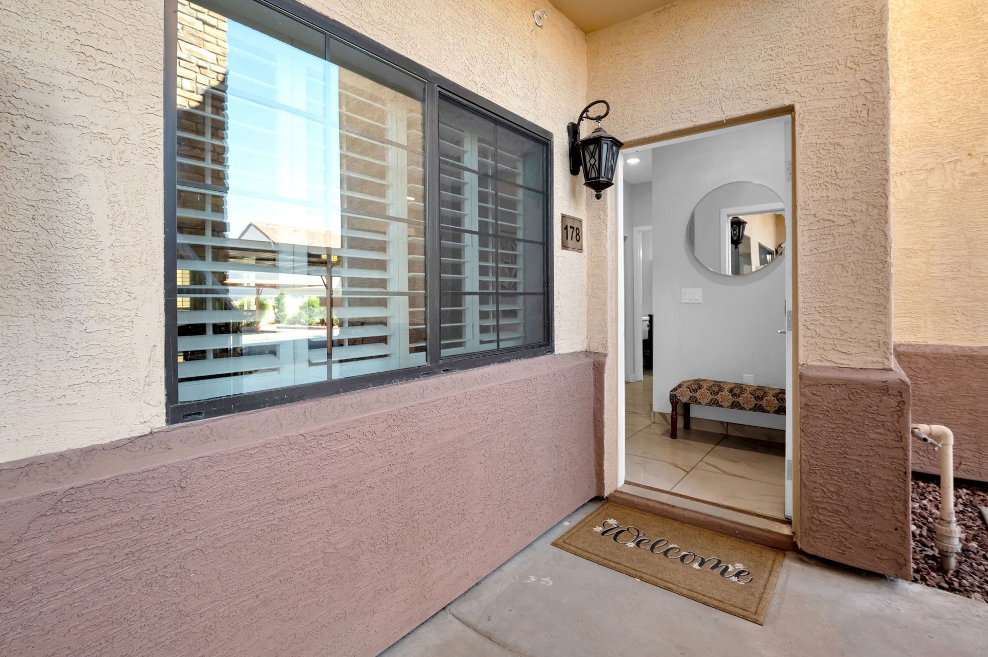 Exterior entrance to a home, with open door revealing interior and welcome mat.