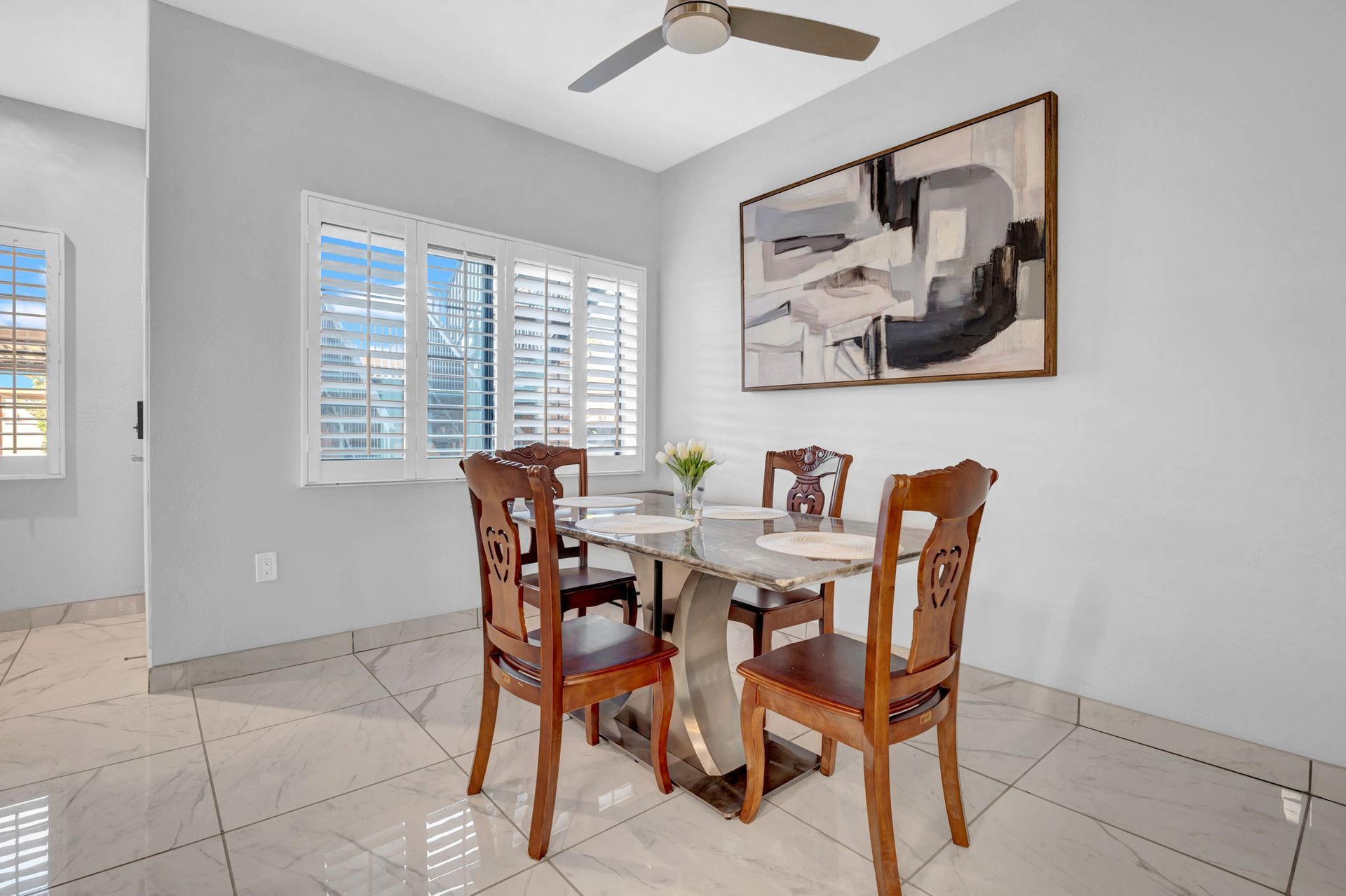 Dining room with table, chairs, art, window, and ceiling fan.