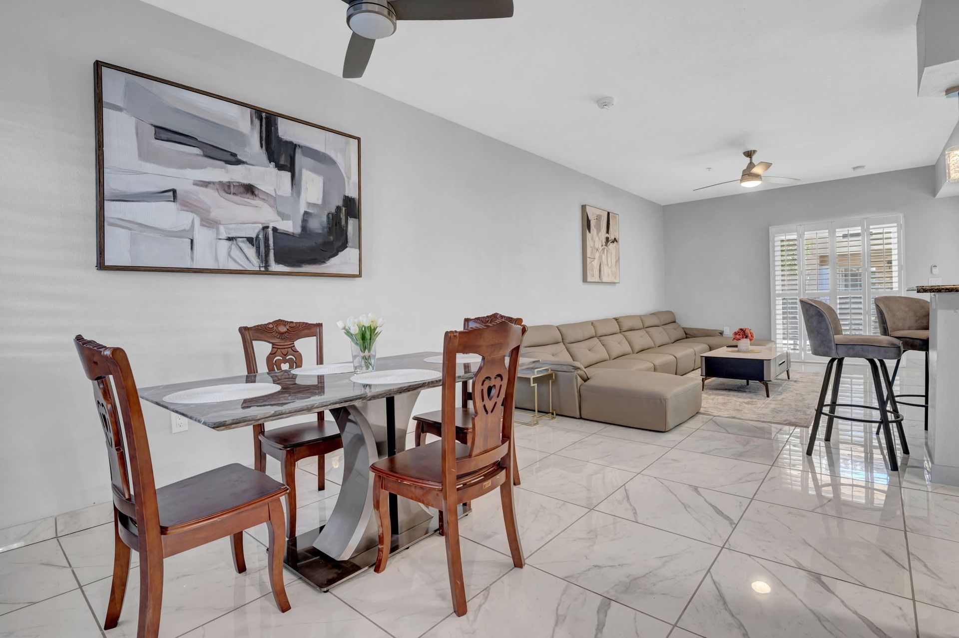 Dining area and living room. Table with chairs, sectional sofa, artwork, and bar stools.