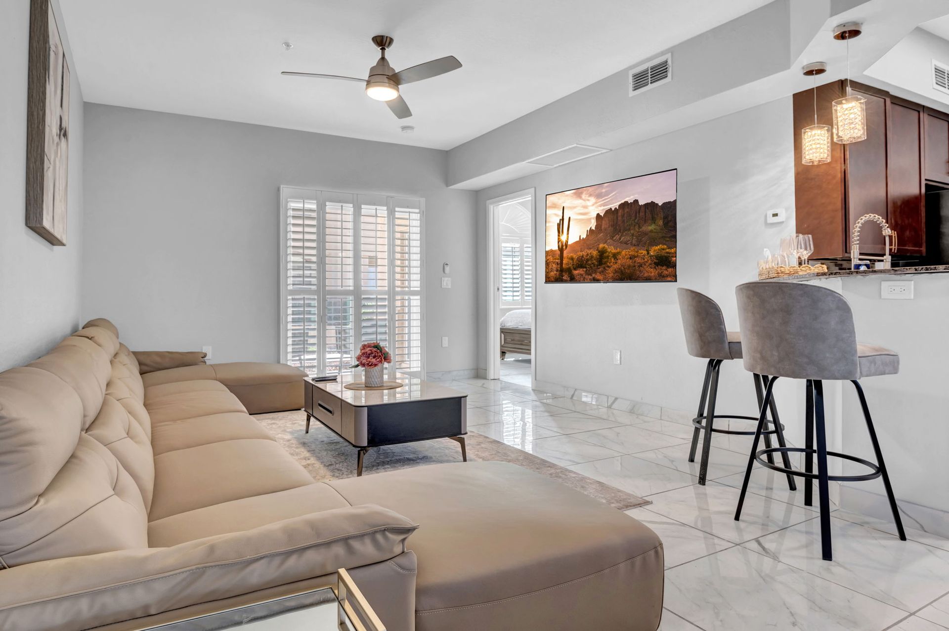 Living room with sectional sofa, kitchen bar, television, and balcony access.