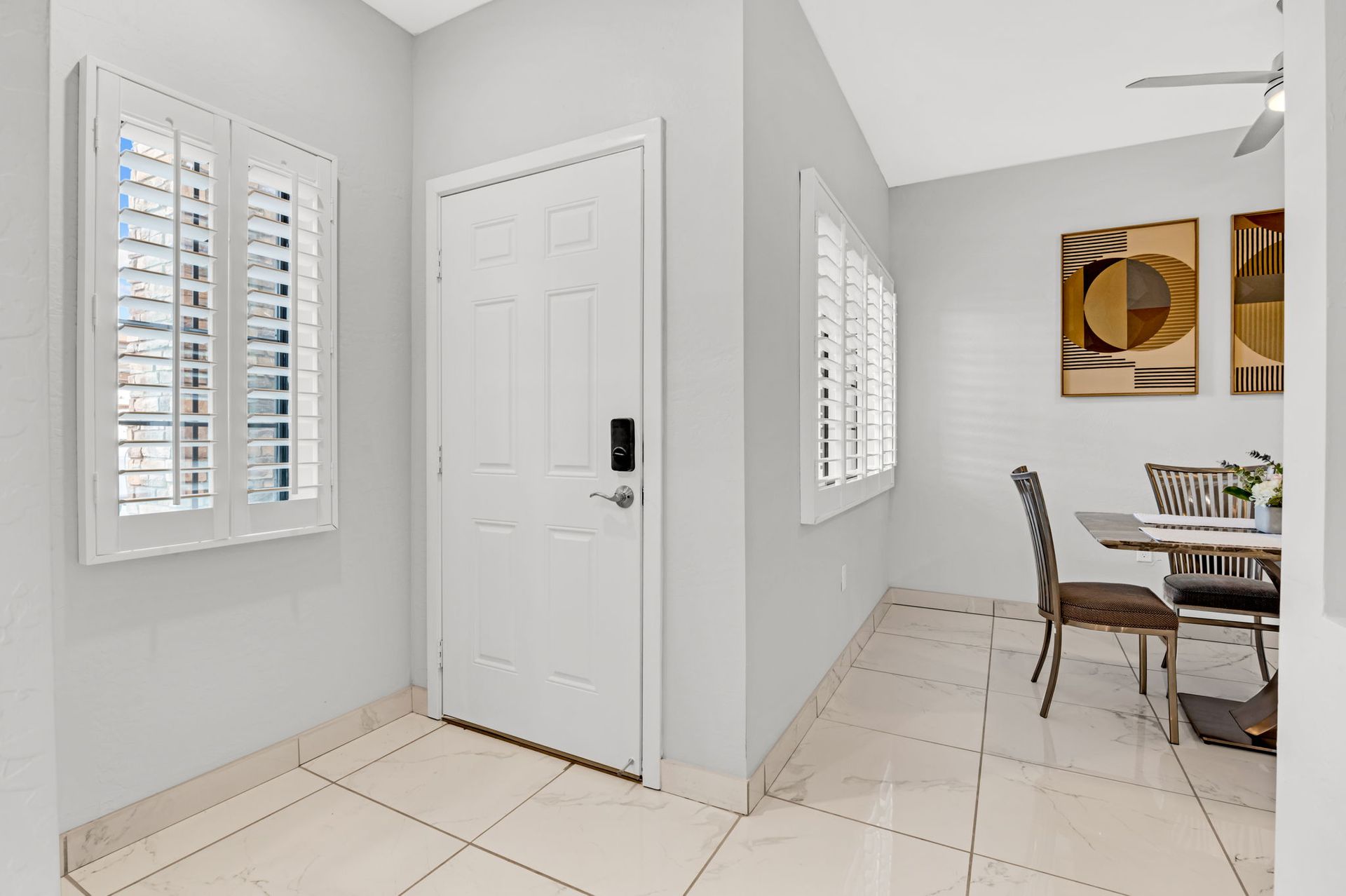 Interior entryway with white door, window shutters, and dining area visible.