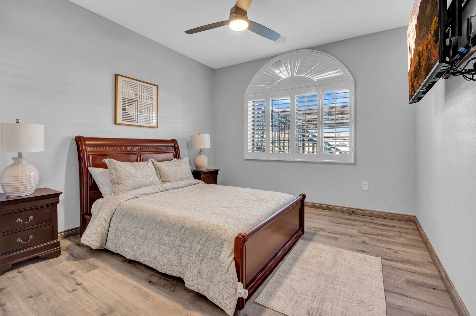 Bedroom with wooden bed, nightstands, and window with shutters.