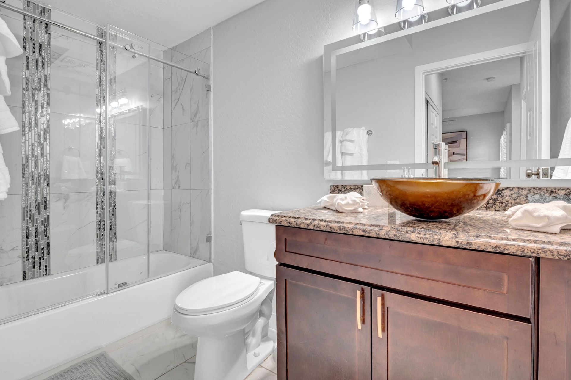 Bathroom with glass shower, brown vanity, and a vessel sink.