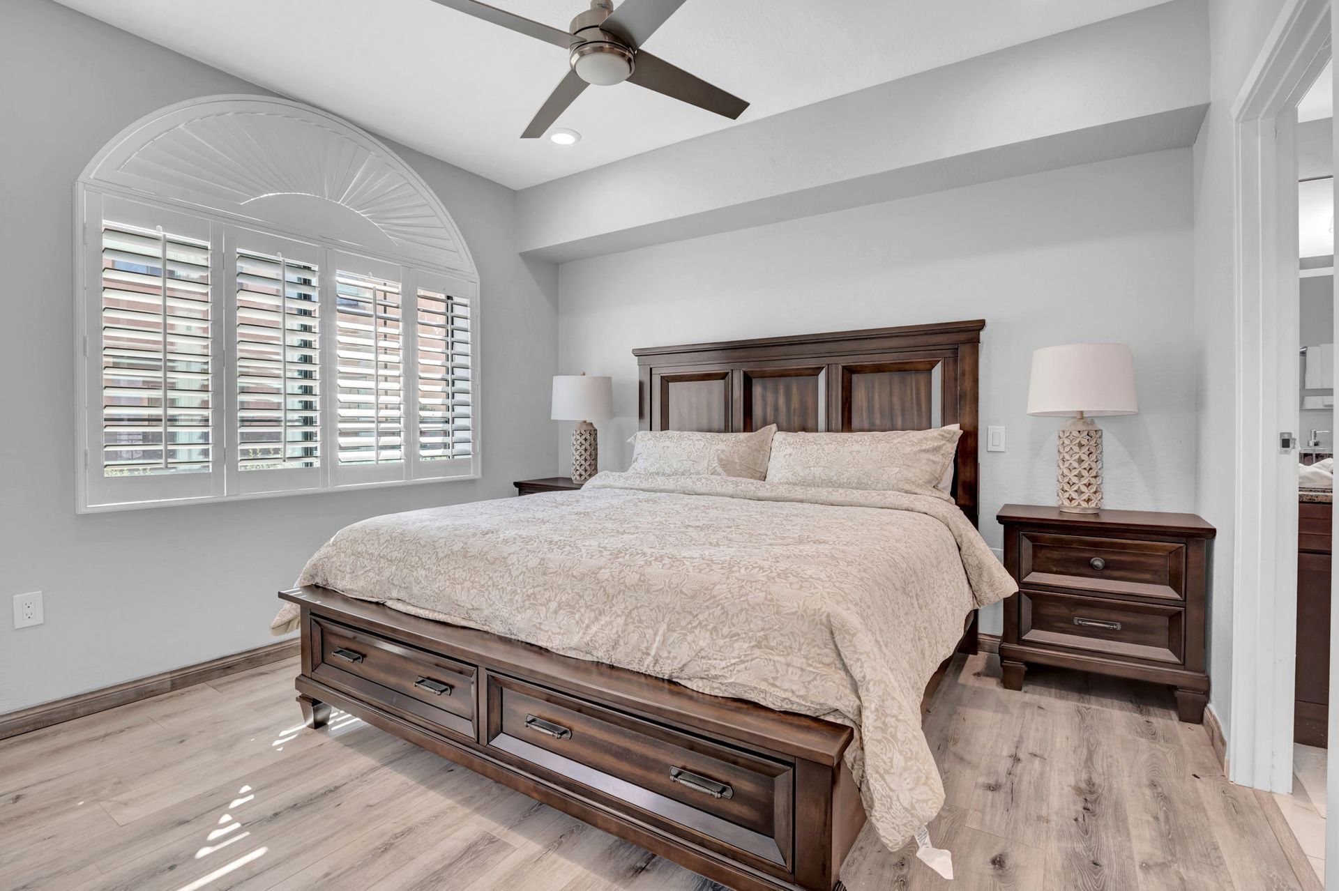 Bedroom with a wooden bed, nightstands, and window with shutters.