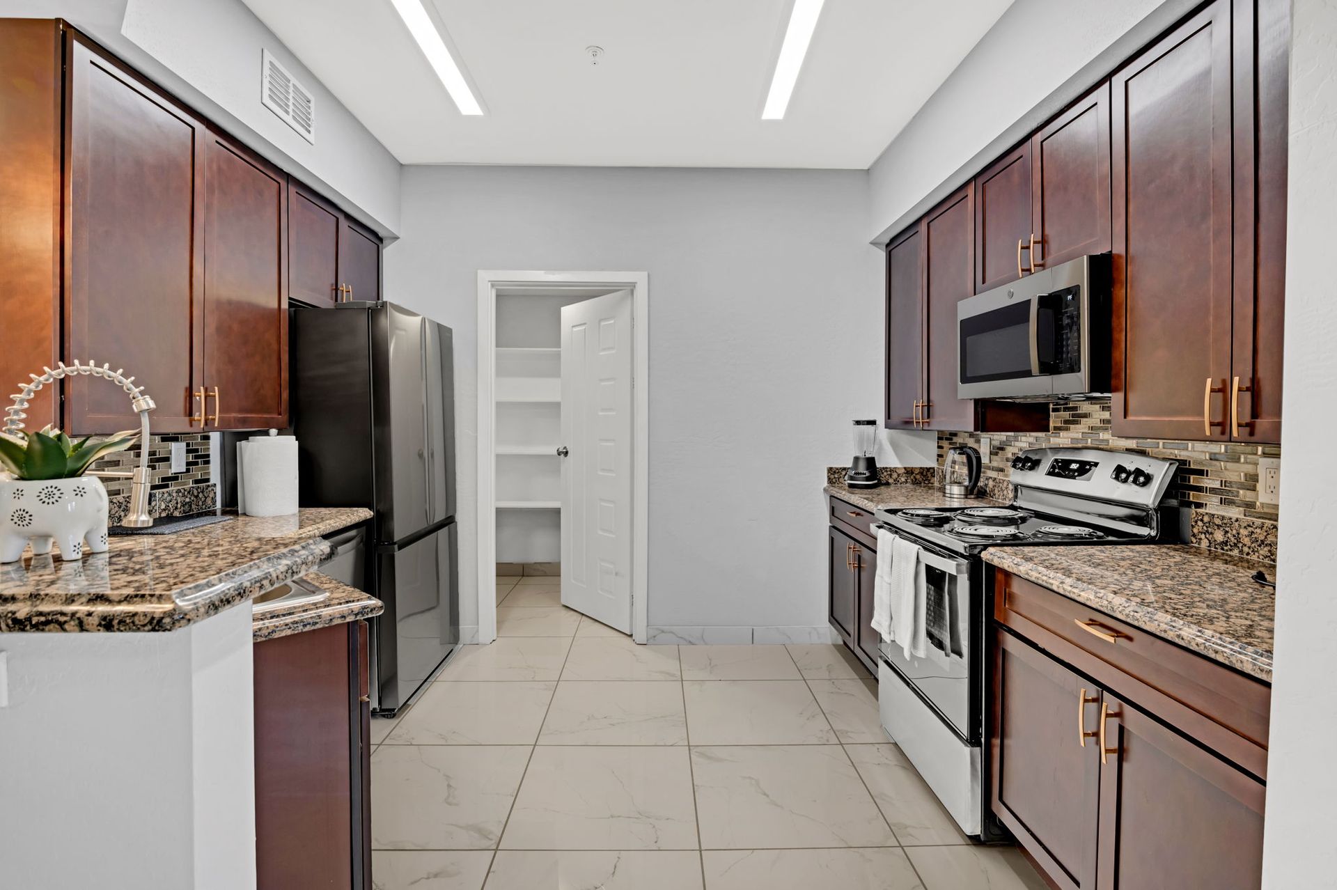 Kitchen with dark wood cabinets, stainless steel appliances, and a pantry.
