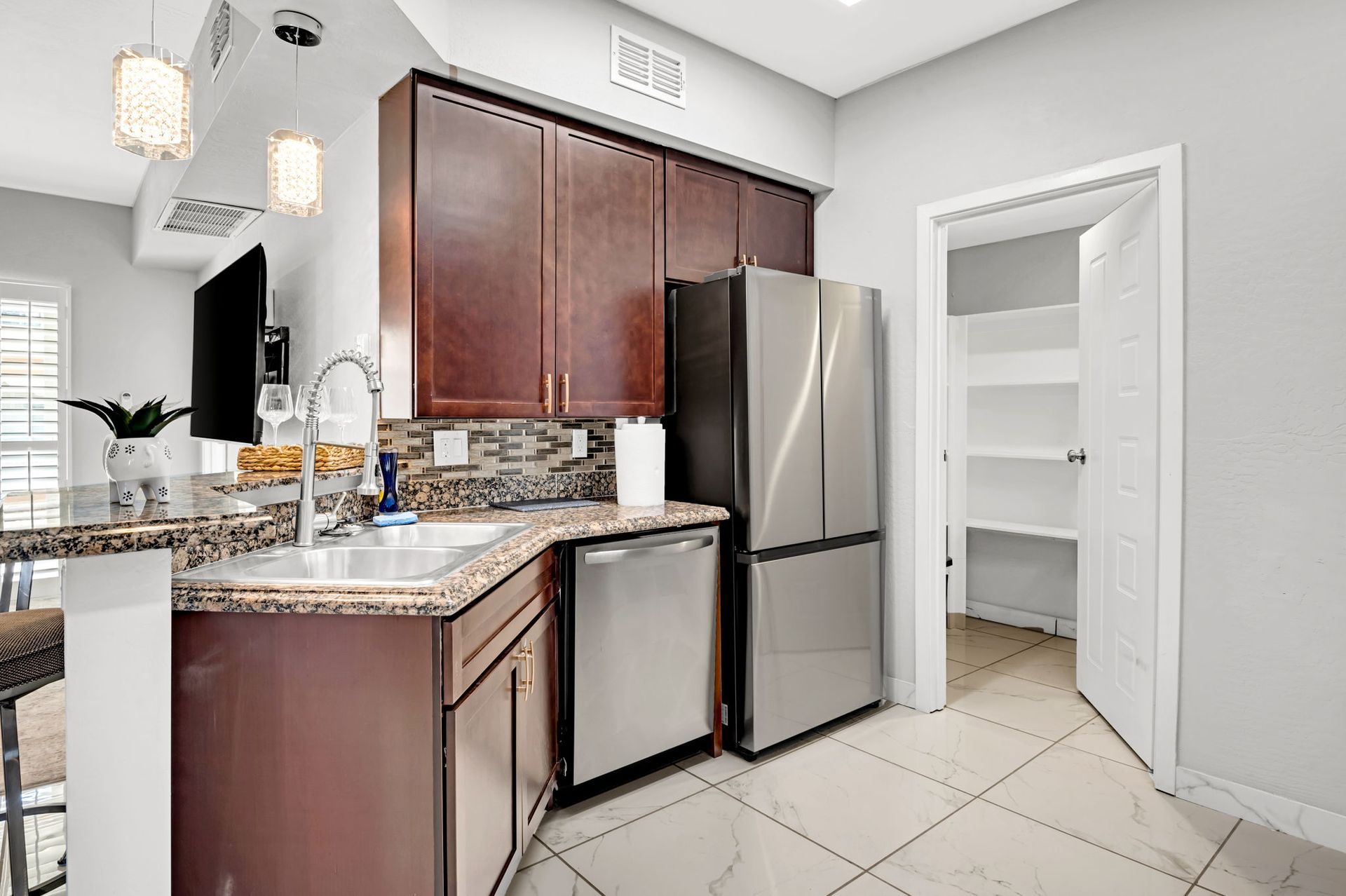 Kitchen with brown cabinets, stainless steel appliances, a pantry, and a countertop with seating.