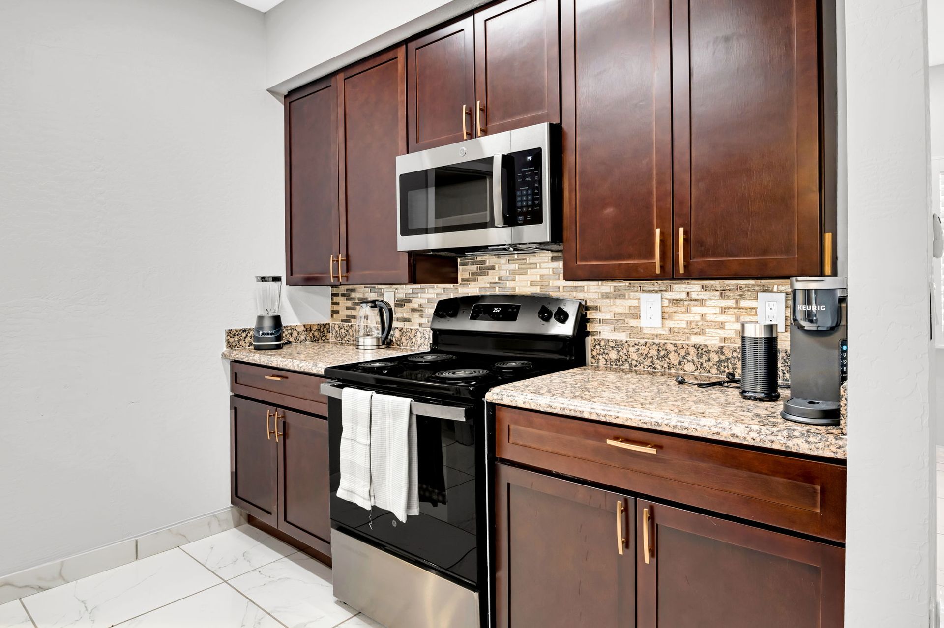 Kitchen with dark brown cabinets, stainless steel appliances, and granite countertops.