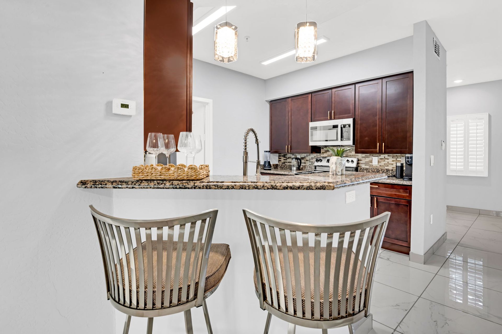 Kitchen with breakfast bar, brown cabinets, granite countertops, two barstools.