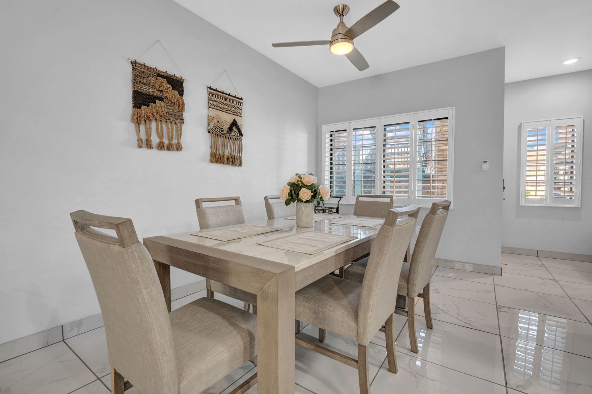Dining room with a table set for six, neutral tones, and wall art.