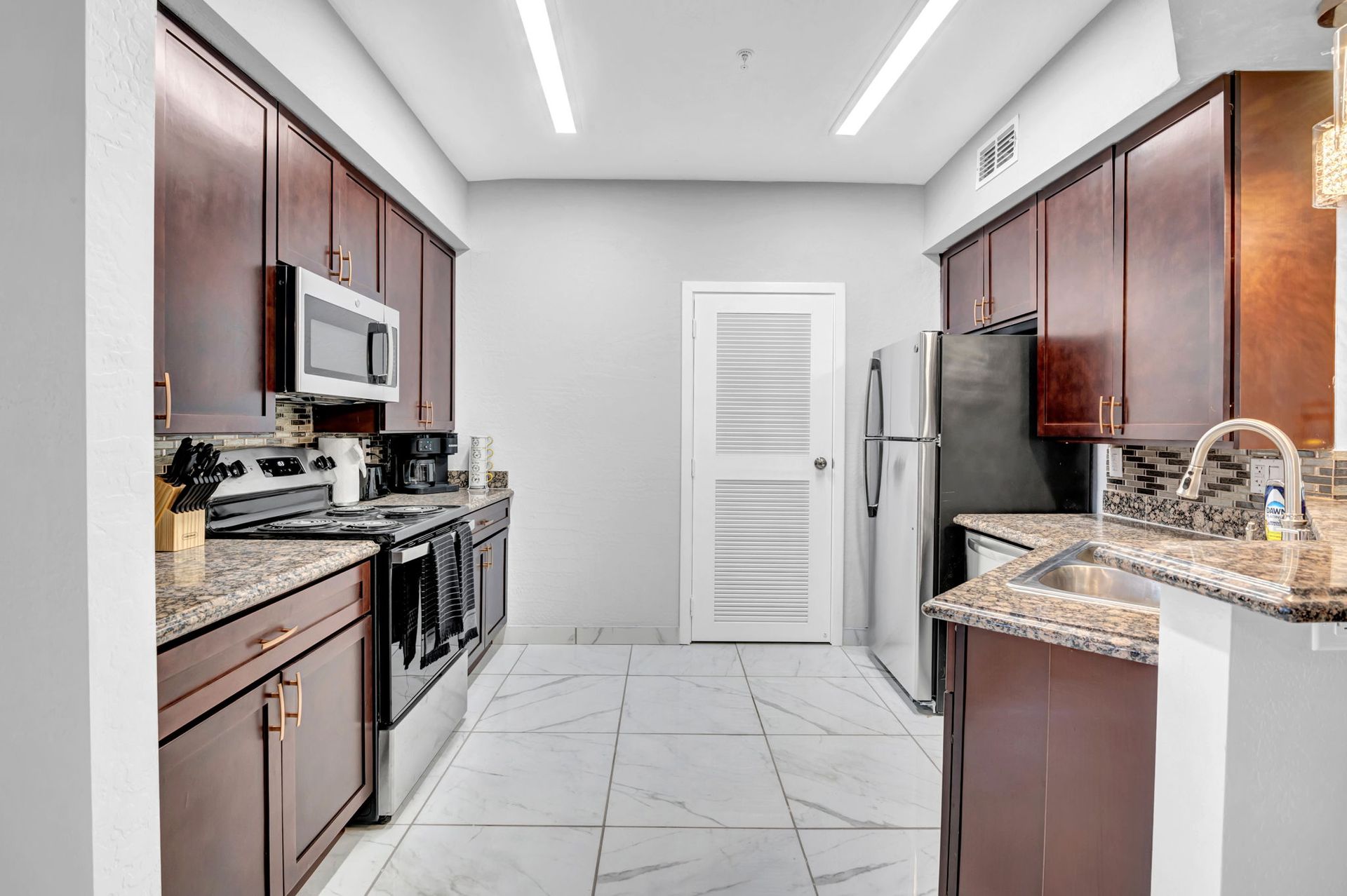 Kitchen with dark cabinets, stainless steel appliances, and granite countertops.