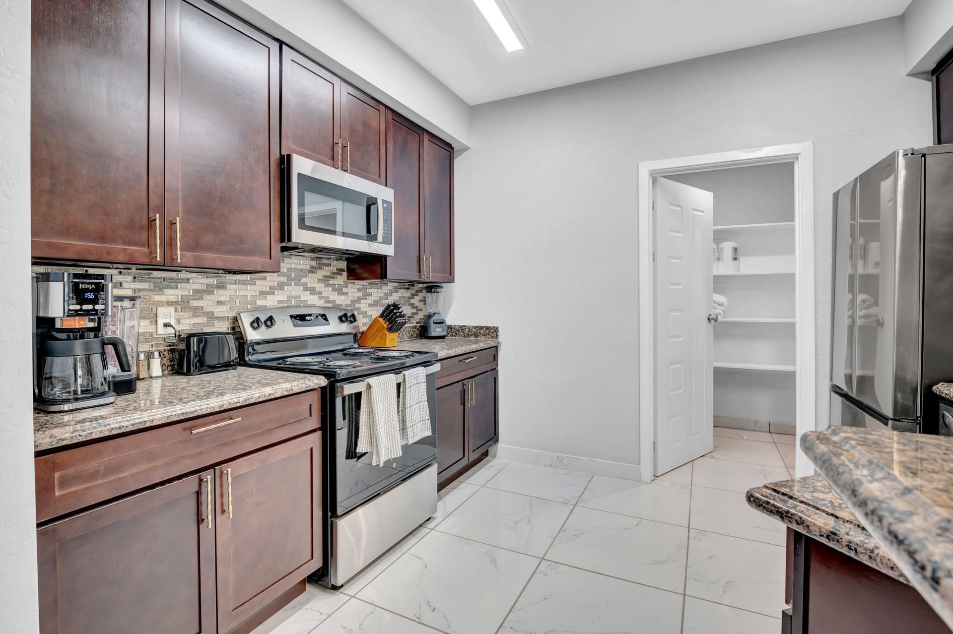 Kitchen with dark brown cabinets, stainless steel appliances, and a pantry.