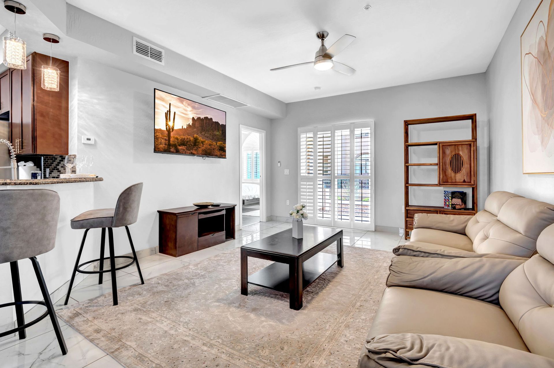 Living room with a beige couch, TV, and bar stools. Light gray walls, light flooring.