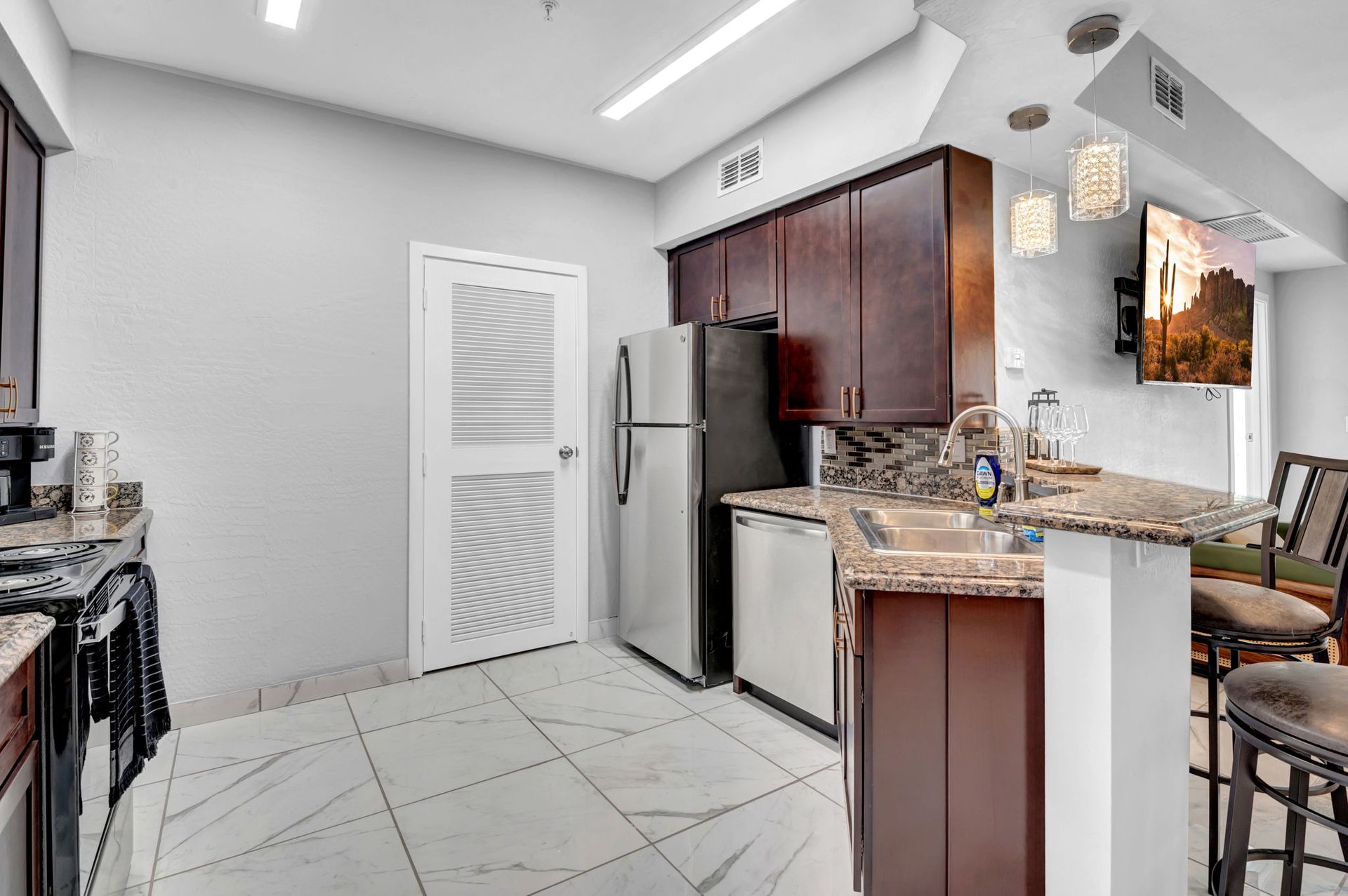 Kitchen with stainless steel appliances, brown cabinets, and a breakfast bar with a TV.