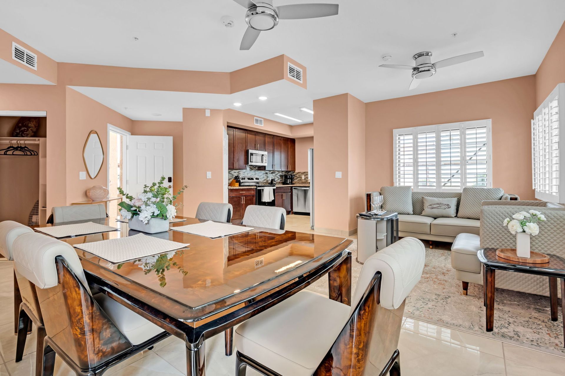 Dining and living area with beige walls, a wood table, and a view into the kitchen.